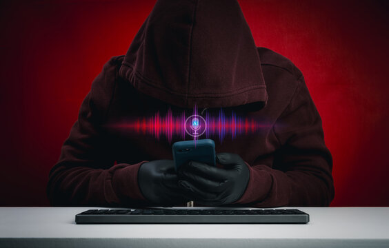 AI voice scam concept with hooded hacker or scammer use smartphone and waveform interface. Deepfake audio manipulation, voice phishing attack, digital identity fraud and AI driven cybercrime threats.