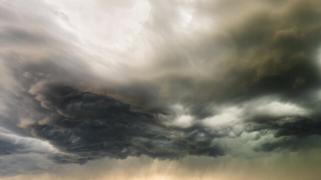 Brooding thunderstorm clouds developing in dark atmospheric sky scene