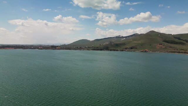 The Lake Sevan, the largest lake in Armenia, surrounded by mountains and clouds. Clear blue water, rugged shoreline, and vast high-altitude landscape captured from a drone in the Caucasus region.