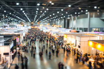 Obraz premium Blurred crowd walking through a busy trade fair exhibition hall with booths and displays, representing international business convention, product showcases, networking, and dynamic event atmosphere.