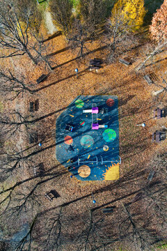 Aerial view of a space-themed playground surrounded by autumn trees and fallen leaves in Turin, Piedmont, Italy.