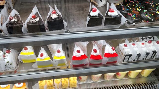 Assorted Cream Pastries and Chocolate Slices in Bakery Display Case