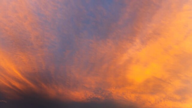 Warm orange sunset light spreading through clouds in a vivid sky scene