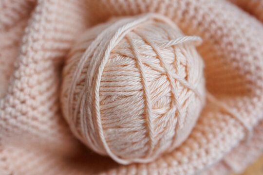 Beige yarn ball on soft knitted fabric background