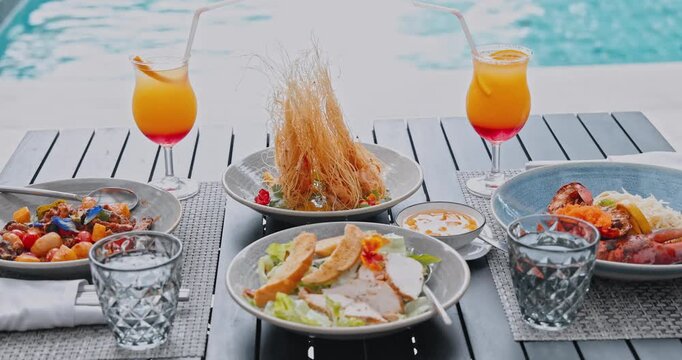 Gourmet plates with fried seafood and fresh salads arranged on wooden table, poolside setting with turquoise water, luxury resort dining and hospitality marketing