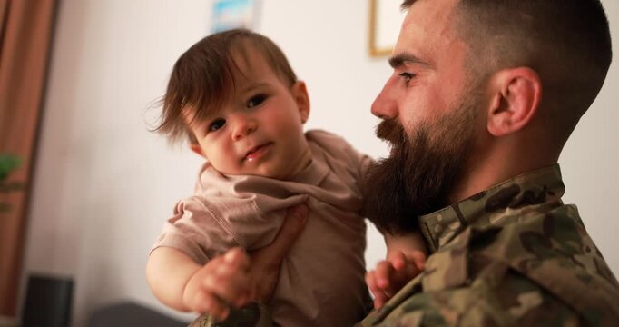 Male american soldier in military uniform hugs his little son at home - Emotional and happy military homecoming concept