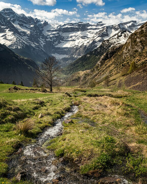 Mountain stream cascades down in the French Pyrenees with the Cirque de Gavarnie in the distance