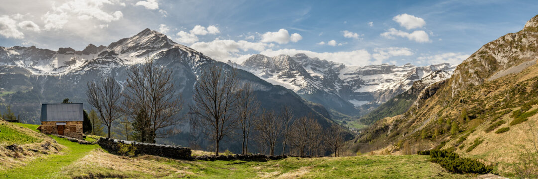Panoramic view of a small stone cottage high in the French Pyrenees with the peak of the mountain, Pim&eacute;n&eacute;, behind and the Cirque de Gavarnie in the distance