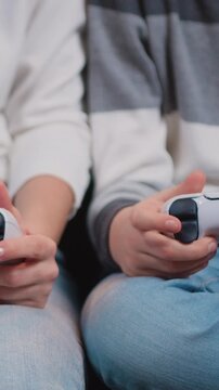Close up of female and child's gamer's hands holding controles and playing video game. Two joysticks, console, gamers, game. Slow motion