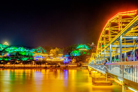 The Yellow River and Lanzhou Zhongshan Bridge are illuminated by brilliant lights at night.