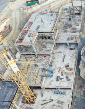 Aerial view of a large construction site featuring concrete foundations, scaffolding, and a yellow tower crane in Avcilar, Istanbul, Turkiye.