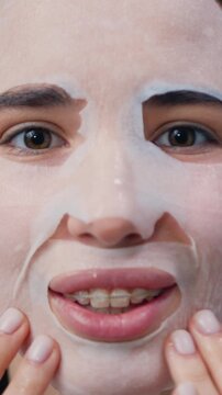 Close up of young girl with facial mask looking in camera on background of the mirror in bathroom. Cosmetic procedure. Beauty spa and cosmetology. Slow motion