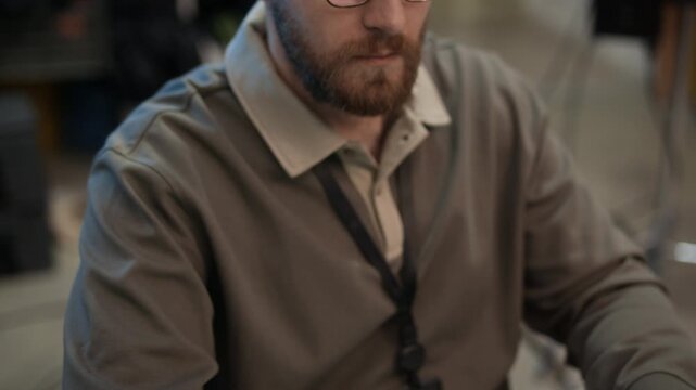 Tilt up shot of Caucasian developer in eyeglasses coding on computer and typing on keyboard at office desk