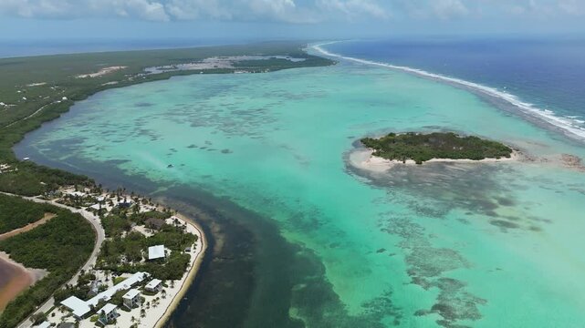 Drone descends over Owen Island, turquoise lagoon, reef flats, and coastline in Little Cayman