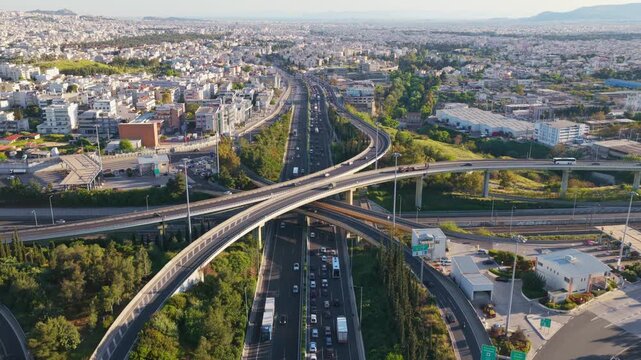 High angle view of a modern multilevel highway interchange with traffic moving through the cityscape, showcasing urban infrastructure and transportation engineering on a sunny day