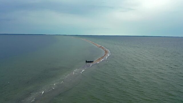 Inflatable RIB boat beached on Mewia Rewa sandbar. Drone footage captures moored vessel on pristine sandbank in scenic Puck Lagoon during summer.