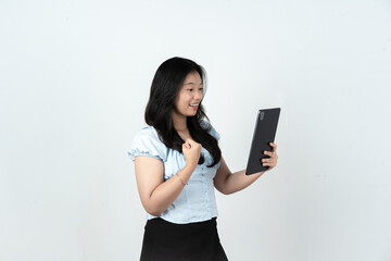 Naklejka premium Excited Asian woman holding a tablet showing winning expression on white background