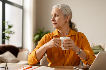 Fototapeta premium Senior woman contemplating memories and mental well being while drinking tea