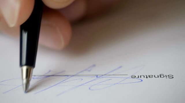 Closeup of a person signing a document with a pen, focus on the signature line and the hand holding the pen