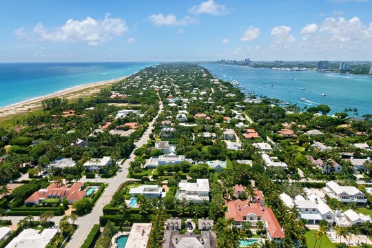 Aerial view of luxury waterfront estates and lush tropical greenery along the peninsula between the Atlantic Ocean and the Intracoastal Waterway in Palm Beach, Florida, United States.