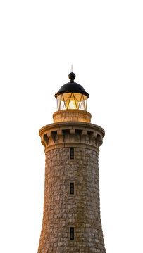 Isolated old stone lighthouse tower with brightly illuminated beacon lamp against a clear sky.