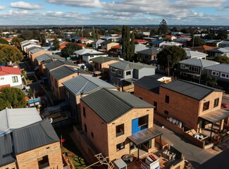 Fototapeta premium New brick veneer townhouses under construction in a suburban neighborhood. Modern dwellings with dark roofs are in close proximity. Residential area development.