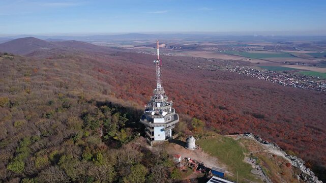 Flight around of Zobor hill with transmission tower, autumn forest, rocky slope, and wide countryside panorama near Nitra, Slovakia.