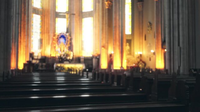 Blurred bokeh church interior with soft defocused altar and pews, warm stained glass light; background backplate copyspace calm.