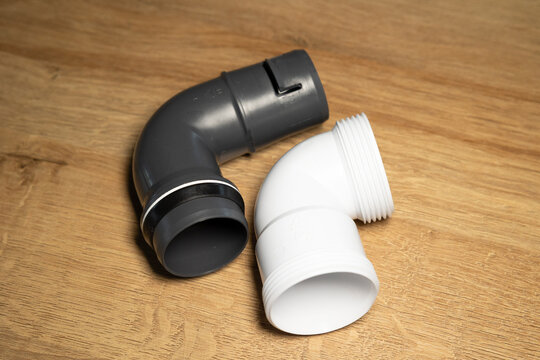 Black and white short plastic pipes, right-angle connecting pipes for use in kitchens, bathrooms, laundry rooms and industrial settings. Plumbing services, repairs, technical equipment, installation.