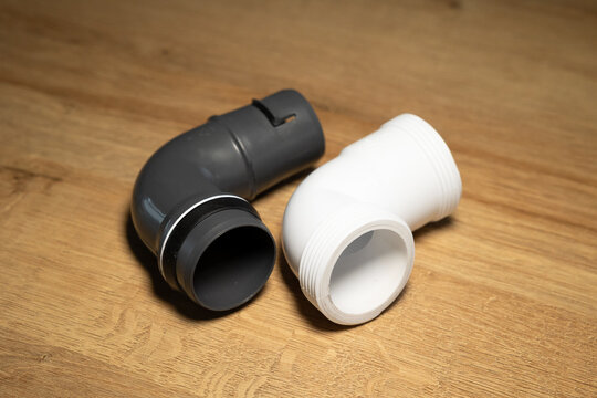 Black and white short plastic pipes, right-angle connecting pipes for use in kitchens, bathrooms, laundry rooms and industrial settings. Plumbing services, repairs, technical equipment, installation.