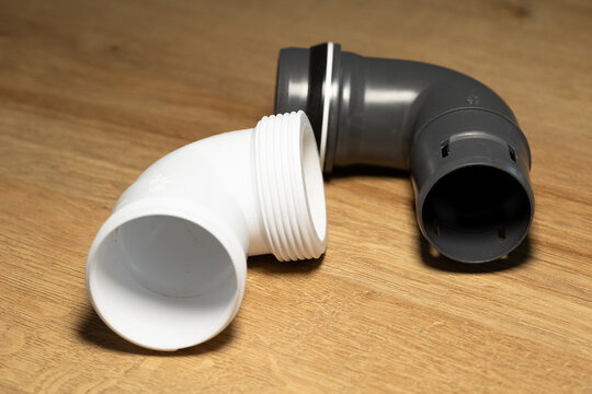 Black and white short plastic pipes, right-angle connecting pipes for use in kitchens, bathrooms, laundry rooms and industrial settings. Plumbing services, repairs, technical equipment, installation.
