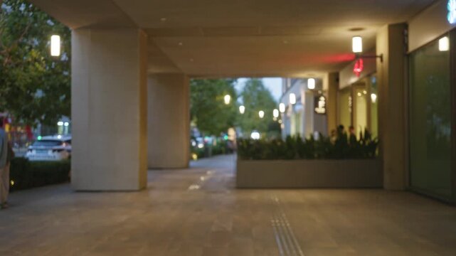 Blurred hotel corridor with soft bokeh lights, planters and tiled floor interior; background backplate copyspace calm.