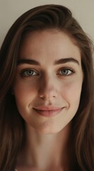 Obraz premium Young woman with gentle smile and kind eyes. She has neat brown hair framing her face. Neutral background. Natural beauty, authentic expression, soft lighting for editorial use.