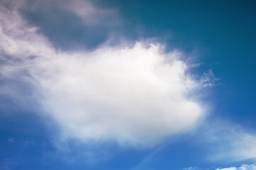 Obraz premium Fluffy cloud against a vibrant blue sky with wispy textures and patterns