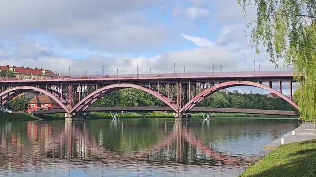 Old Bridge Stari Most over Drava River in Maribor, Slovenia. Scenic view of the historic red Steel Bridge (Stari Most) in Maribor city. Beautiful symmetric reflection in the Drava river.
