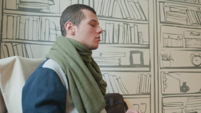 White man leaning toward laptop, curious expression and soft smile, green scarf and casual sweater, illustrated bookshelf wallpaper backdrop, closeup of hands typing on keyboard, scenes