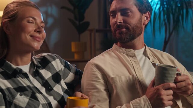 Caucasian happy middle-aged couple drinking tea holding cups in evening smiling spending quality time happiness relationship spouses husband wife man with woman drink beverage health medicine remedy