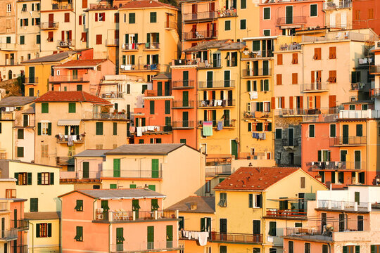 View of colorful historic houses of Manarola village stacked on the hillside during golden hour in Manarola, Liguria, Italy.