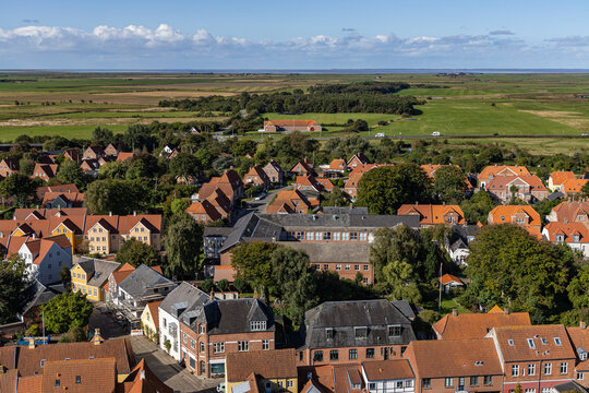 View of the historic red-tiled rooftops and traditional architecture of the old town under a bright blue sky in Ribe, Denmark.