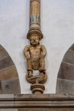 View of an intricate stone carving of a squatting figure supporting a column inside the historic Ribe Cathedral Ribe, Denmark.