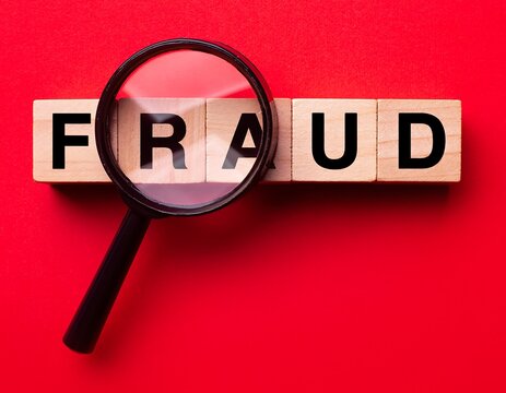 Magnifying Glass Examines Fraud Word on Red Background.