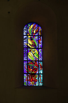 View of a colorful abstract stained glass window inside Ribe Cathedral with vibrant light filtering through the dark stone wall Ribe, Denmark.