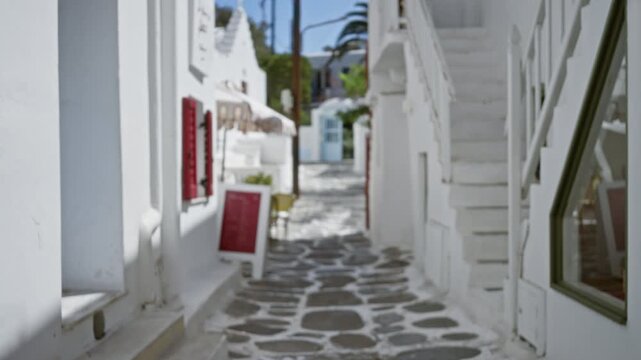 Mykonos narrow cobblestone lane with whitewashed buildings, defocused bokeh street; background backplate copyspace calm.