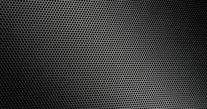 Black Perforated Metal Mesh. Smooth slow movement across extreme close-up of dark perforated metal grid with dramatic side lighting.