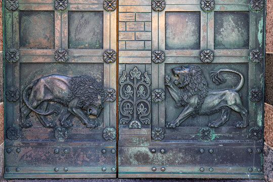 View of the ornate bronze doors of Ribe Cathedral featuring detailed lion reliefs and floral patterns in Ribe, Denmark.