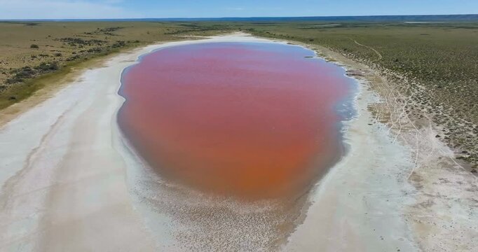 4K video; slow forward drone flight over small salt lake colored red by the presence of salt loving micro-organisms, Southeast Patagonia, Argentina