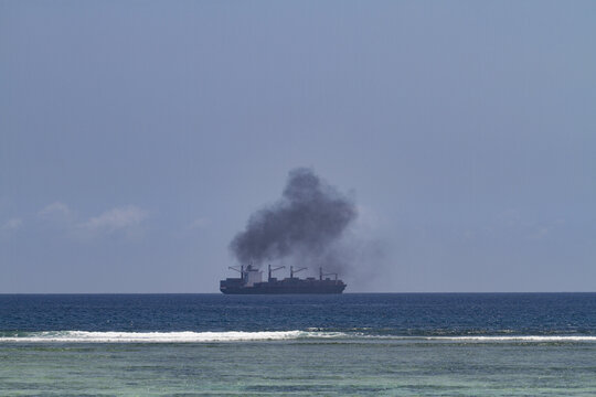 View of a large cargo ship emitting thick black smoke on the horizon from Tiwi Beach Tiwi, Wilaya ya Kwale, Kenya.