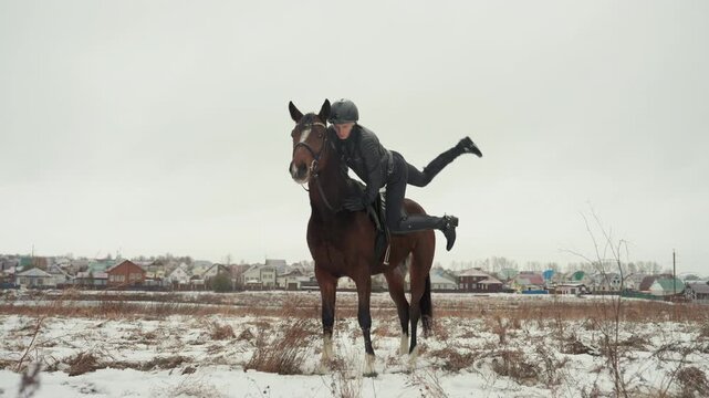 Rider on horse in snowy field practicing controlled dismount and balance during equine lesson, slow winter light, distant village skyline, tandem focus on rider and horse connection and posture