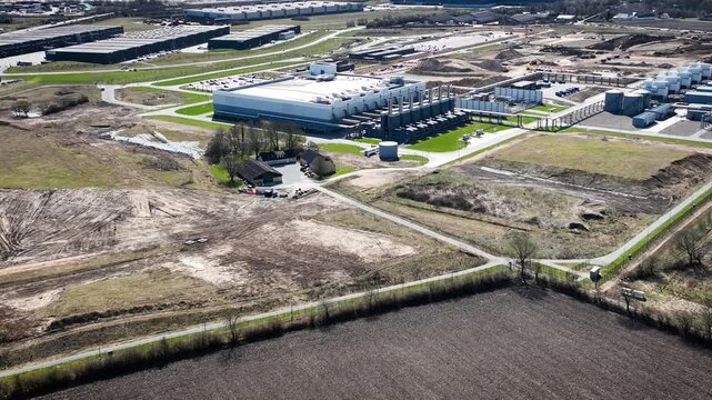 Aerial footage of a data center campus with computing facilities, energy systems, cooling infrastructure, and expansion areas under construction in an industrial technology complex.