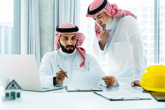 Saudi businessmen coworkers analyzing real estate architecture project plans